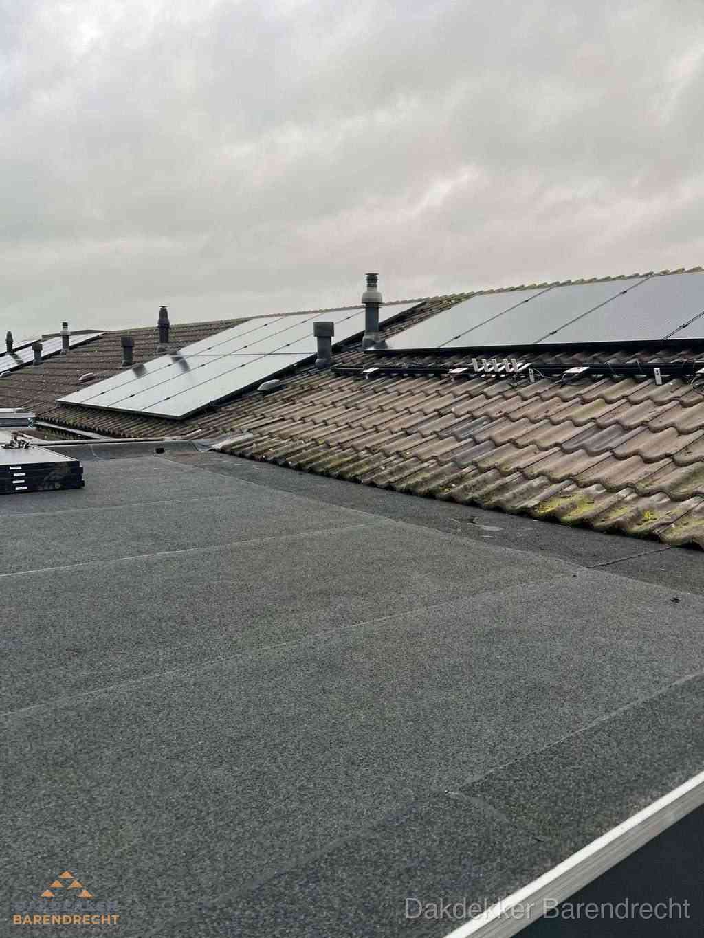 Plat dak inspectie met bitumen bedekking naast schuin pannendak in Barendrecht