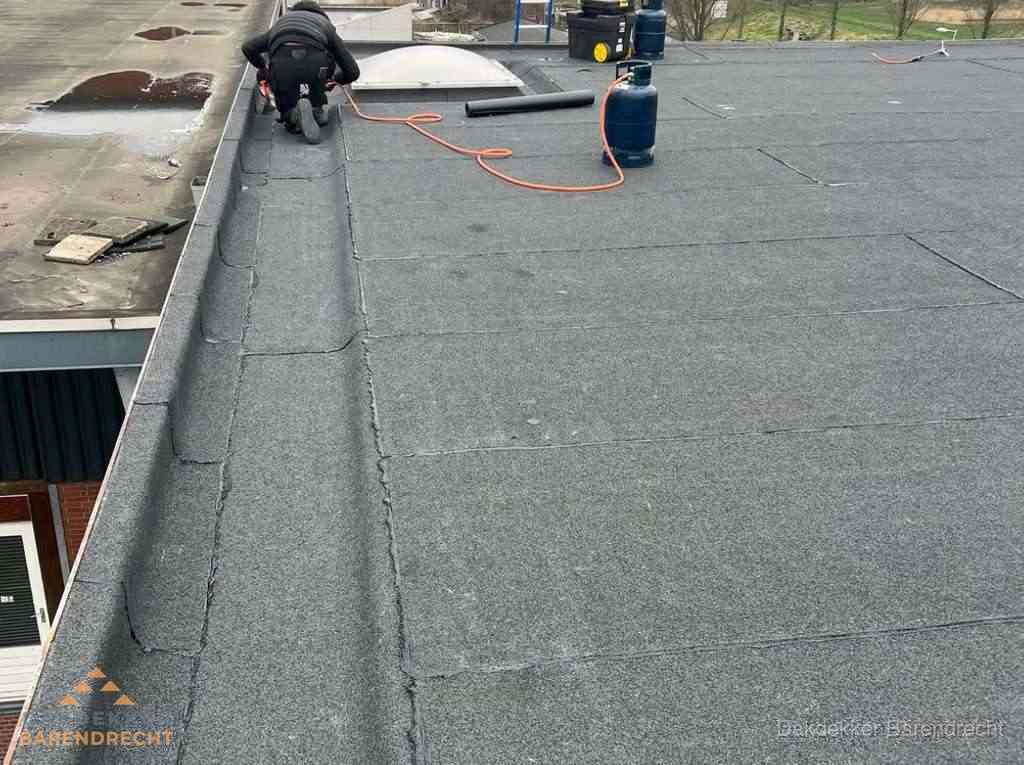 Dakdekker repareert bitumen dakbedekking op groot plat dak in Barendrecht